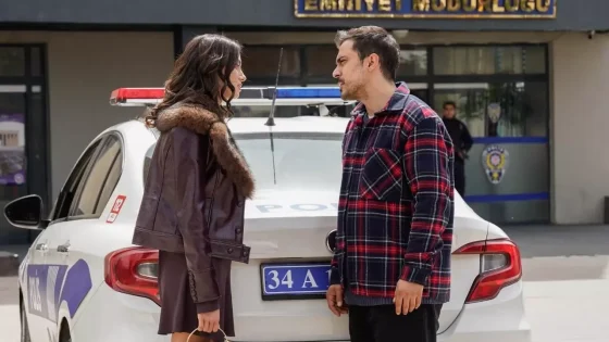Two people stand and talk beside a white police car with a red-blue light bar, outside a police station labeled Istanbul Emniyet Müdürlüğü (Istanbul Police Department).