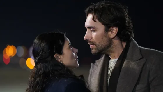 Two people facing each other at night, sharing a close, intimate moment with blurred city lights in the background.