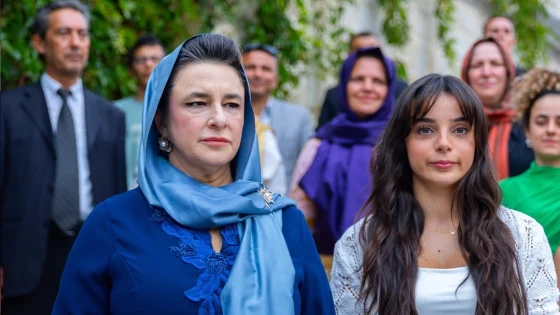 Two women in the foreground at an outdoor formal gathering, one in a blue headscarf and the other with long dark hair, with a diverse group behind them.