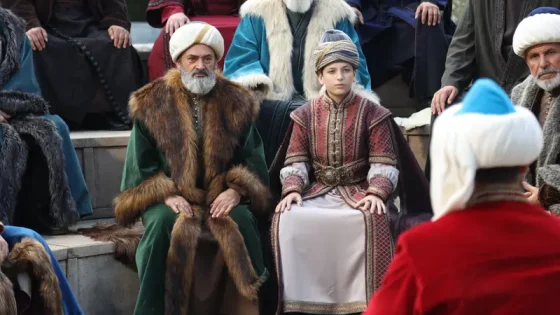 Man and boy in ornate, fur-trimmed robes seated on stone steps during a cultural festival or performance.