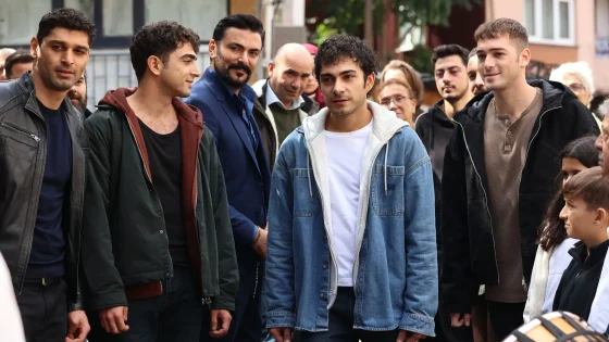 Group of casually dressed adults standing together on a street, some looking toward the camera in an urban outdoor gathering.