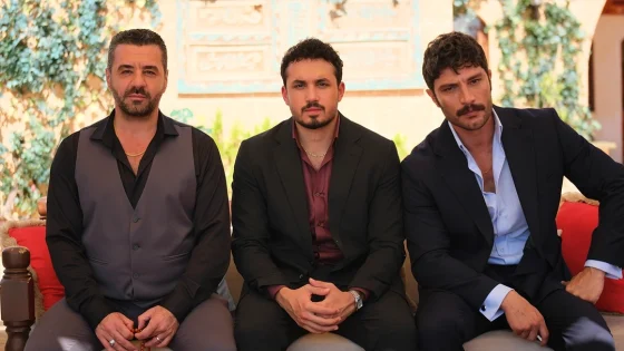 Three men in suits sitting outdoors on a red-cushioned bench, posing for the camera.