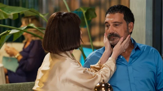 Woman gently holds a man's face with both hands during a warm moment in an office setting