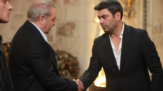 Two men in dark suits shake hands in a warmly lit indoor setting, suggesting a formal greeting or agreement.