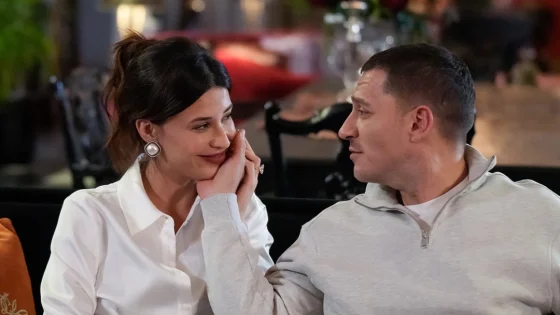 Couple seated in a restaurant, the man gently cupping the woman's face as they smile at each other.
