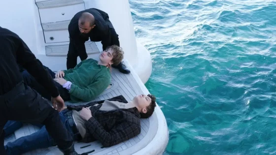 Rescuers pull a man onto a white inflatable boat as two others stand by; turquoise sea surrounds them.